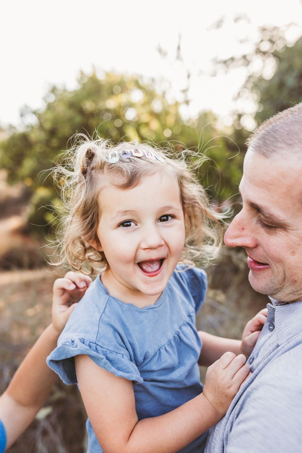 Candid moments of joyful laughter and connection during an outdoor family portrait session.