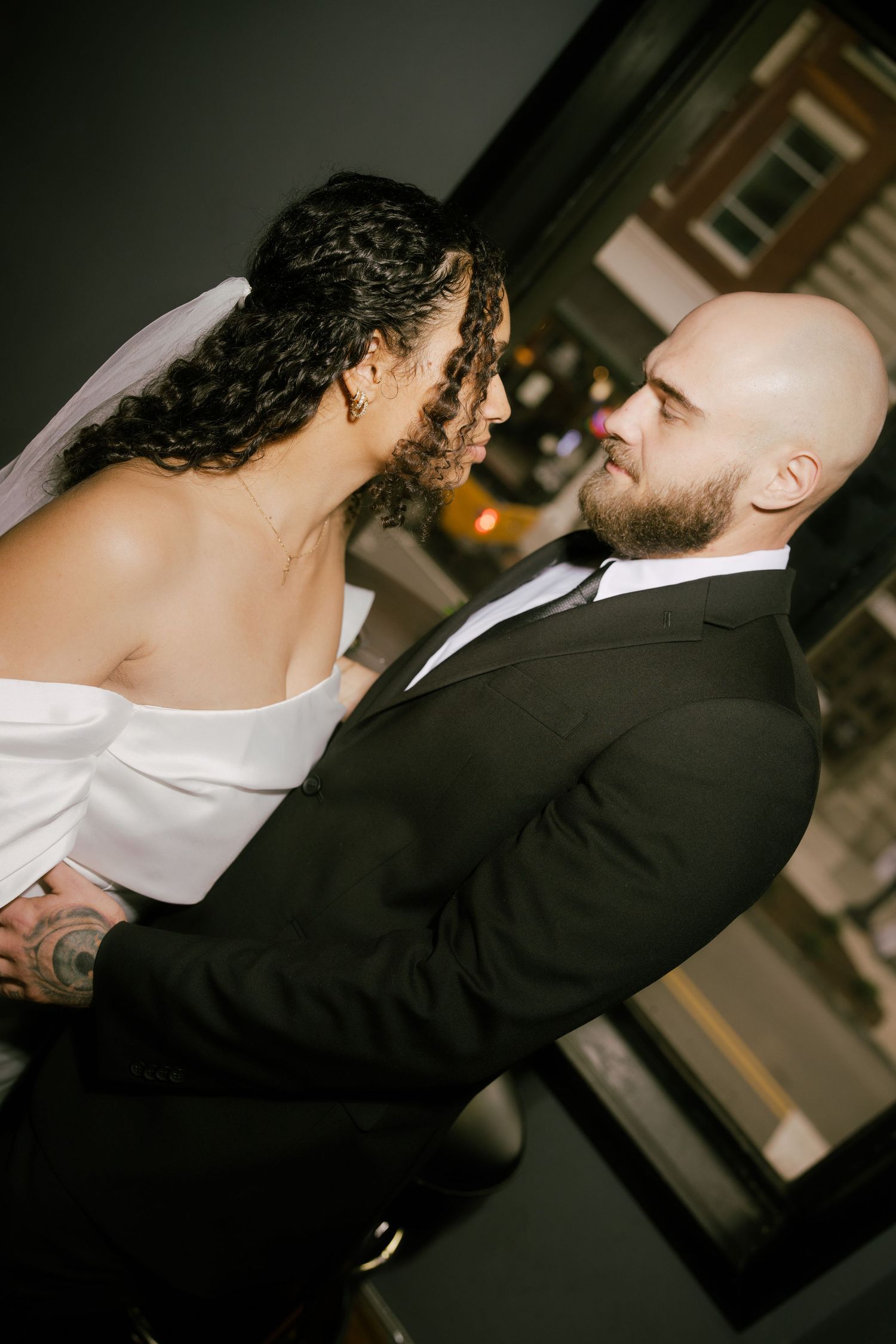 A couple in formal attire share an intimate kiss during what appears to be a wedding celebration.