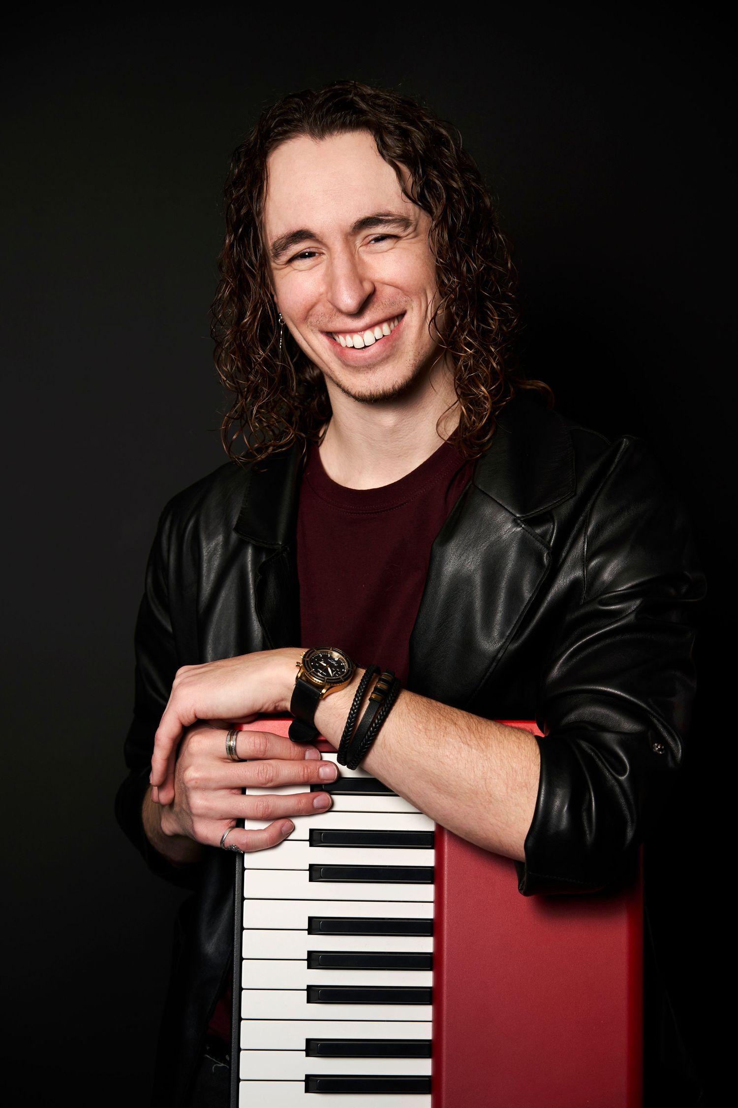 Artistic portrait series showing a musician in a leather jacket posing with a red keyboard instrument against dark backdrop.