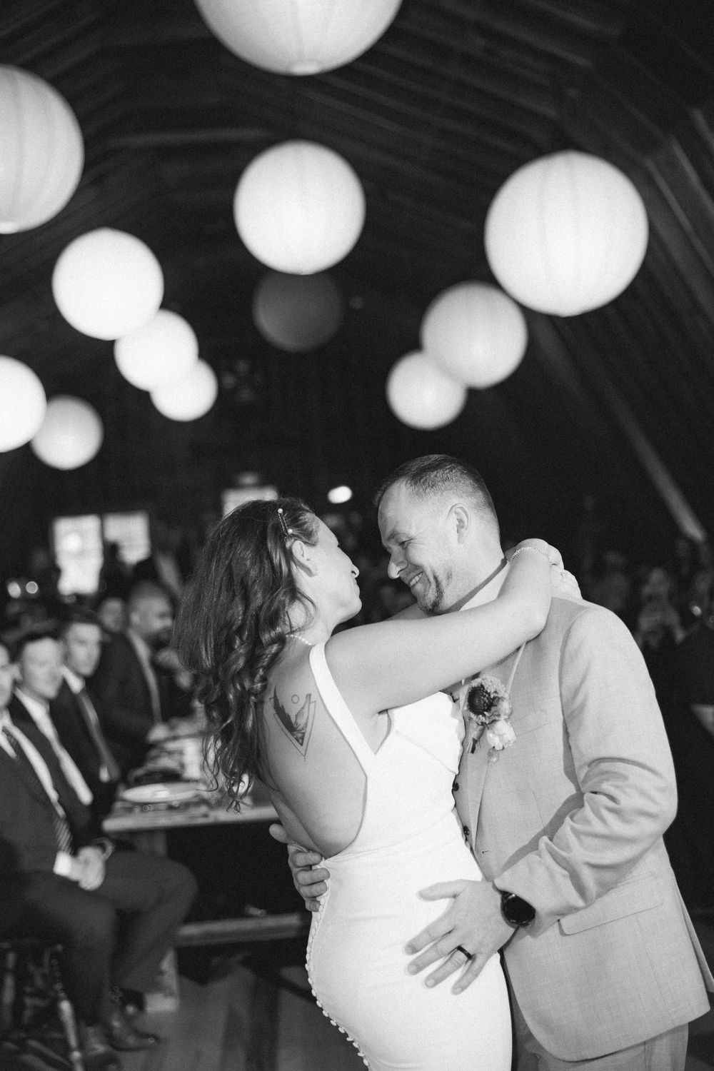 Wedding guests dance under white paper lanterns during an evening reception celebration.