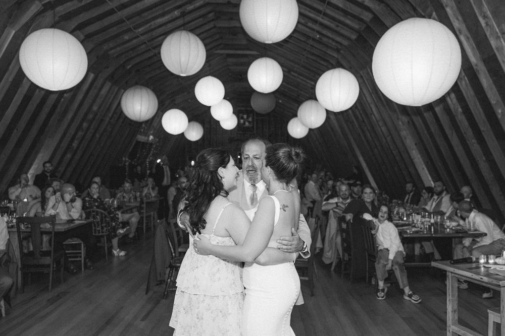 A romantic first dance at a wedding reception under glowing white paper lanterns in a rustic venue.
