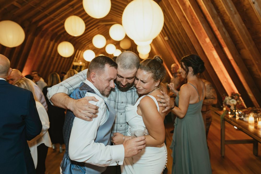 Joyful celebration on a dance floor with white paper lanterns hanging from wooden beams.
