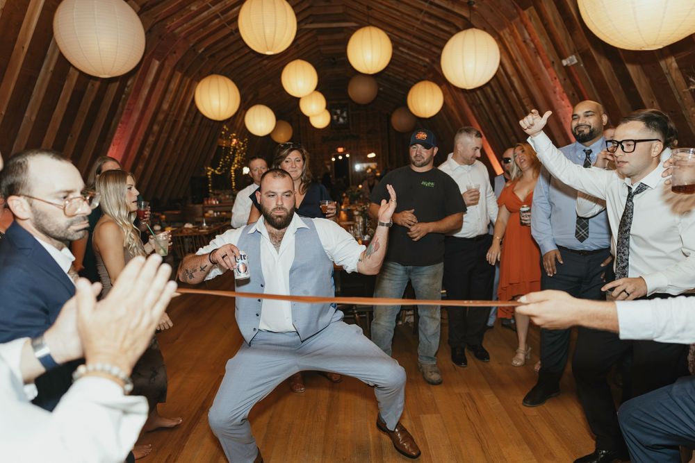 Paper lanterns illuminate a rustic wooden barn ceiling during an evening wedding reception.