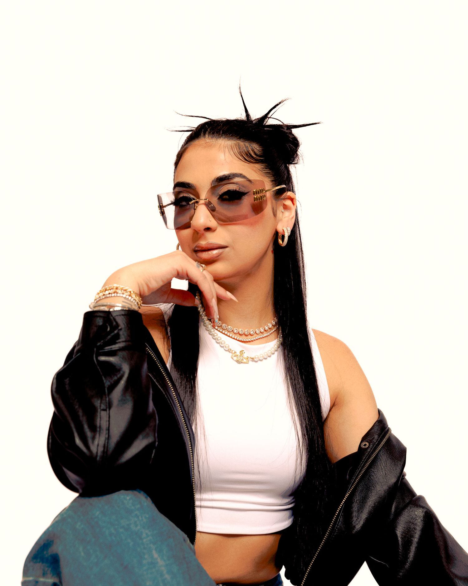 Four fashion portraits showing someone in a black leather jacket and white top striking dramatic poses against a white backdrop.