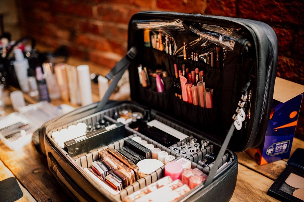 Close-up view of vintage makeup products and cosmetics arranged on a wooden surface with professional brushes and tools.