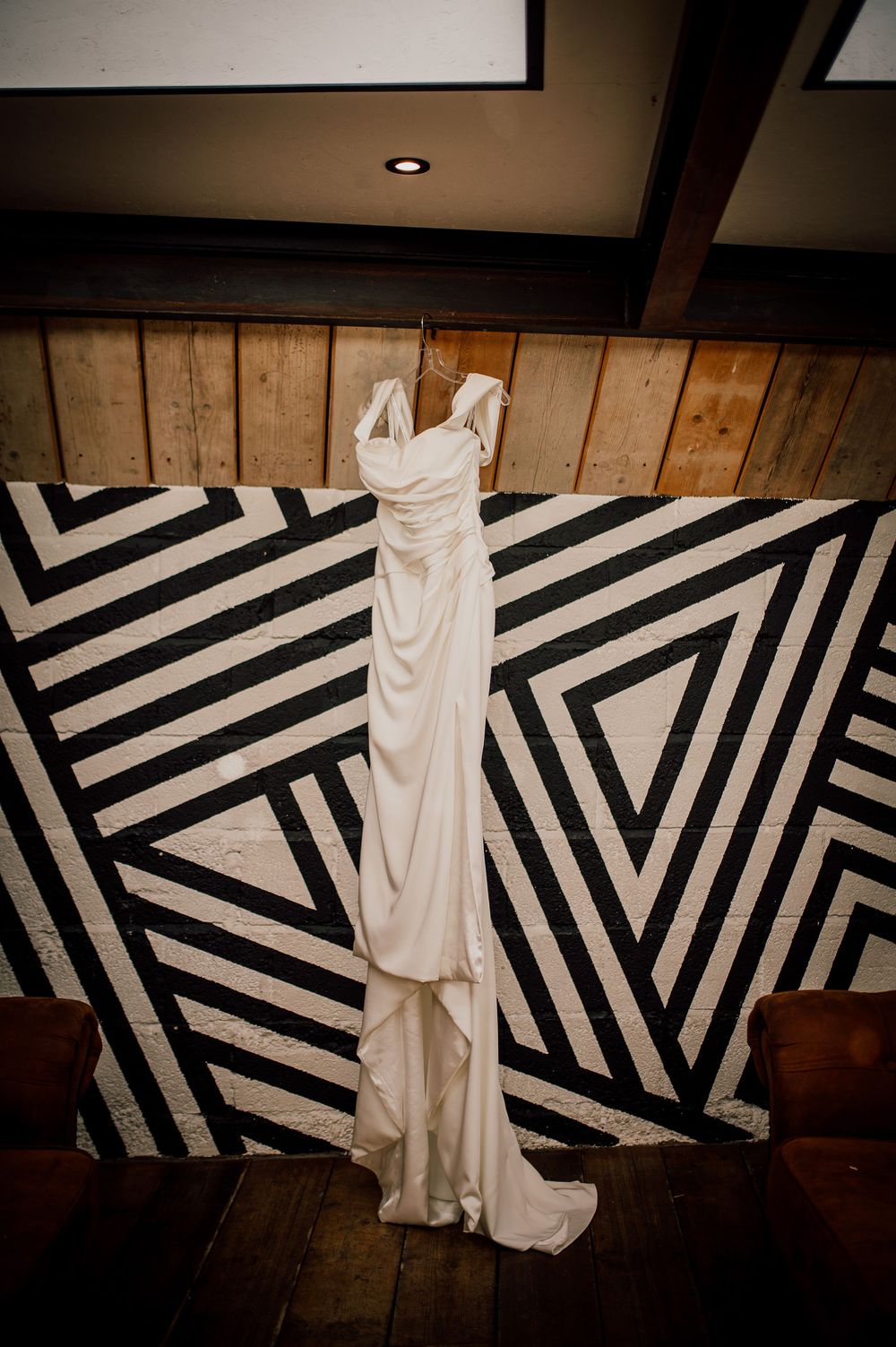 A white wedding dress displayed against a black and white geometric striped wall creates a striking contrast.