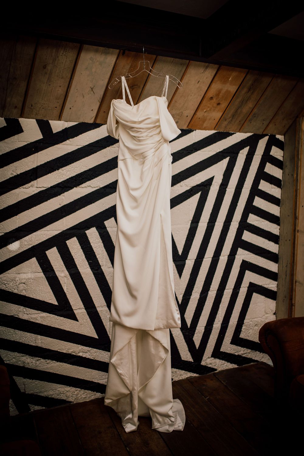 White dress hanging against a geometric black and white striped wall creates dramatic contrast in artistic photography.