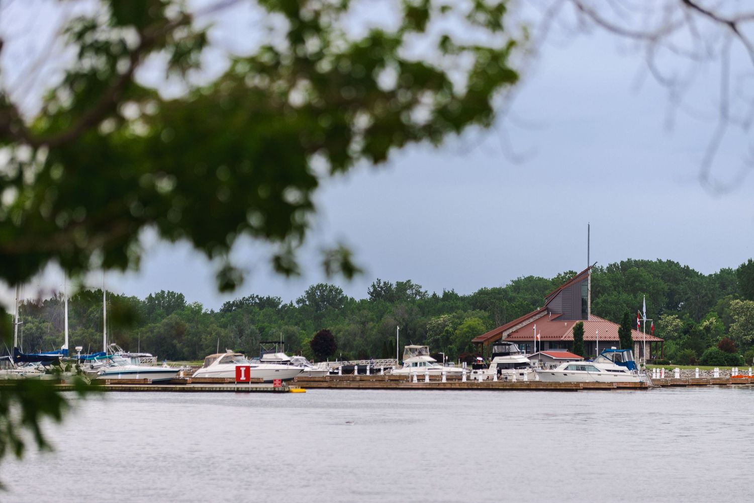 Panoramic view of waterfront buildings and docks along a tropical coastline with lush green hills in the background.