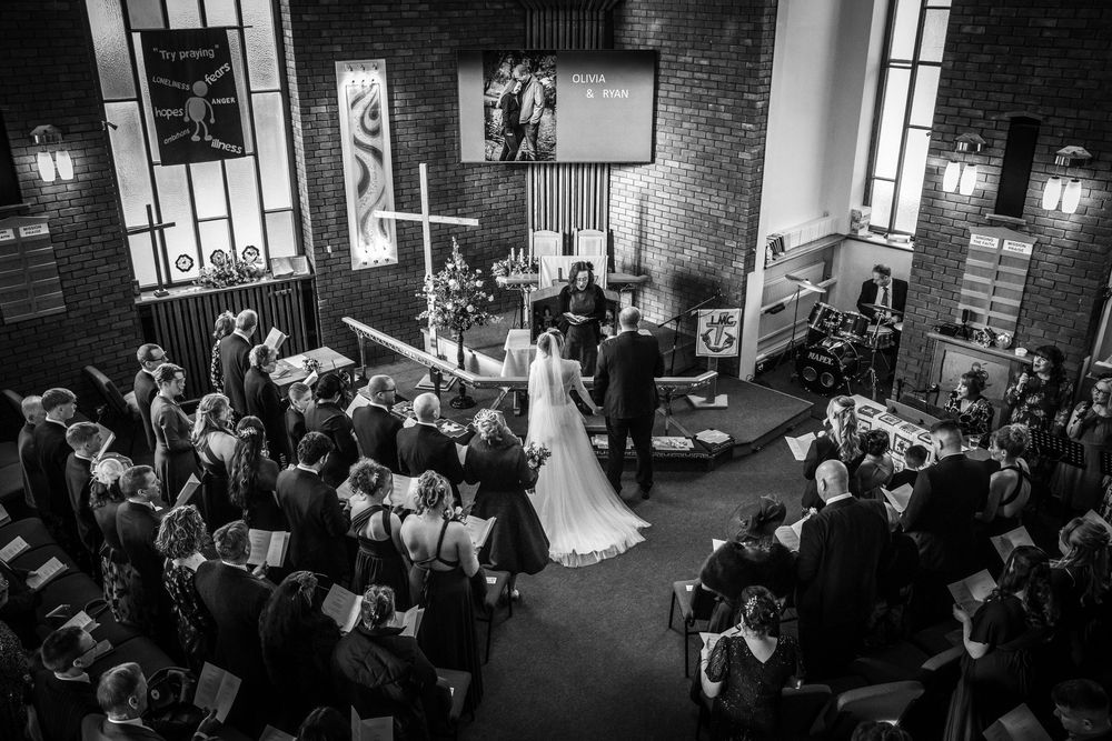 Aerial black and white view of a bride and groom at the altar in a brick church.