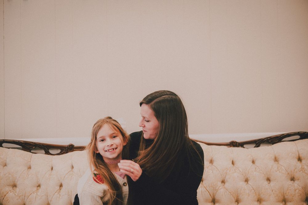 Two people share a tender moment while sitting together on a cream-colored tufted couch.