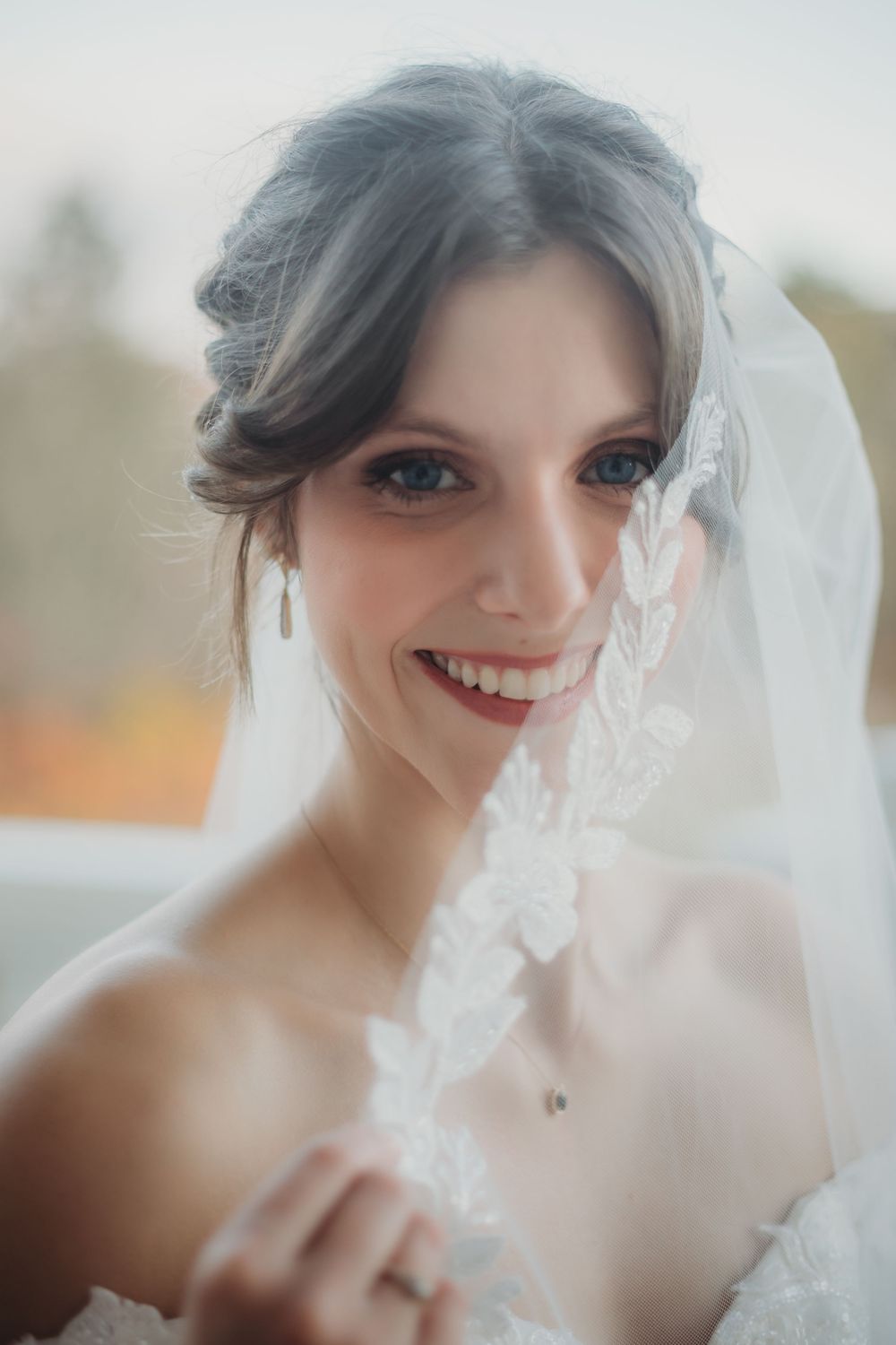 A bride in a white veil smiles radiantly while getting ready on her wedding day in Huntsville Alabama.