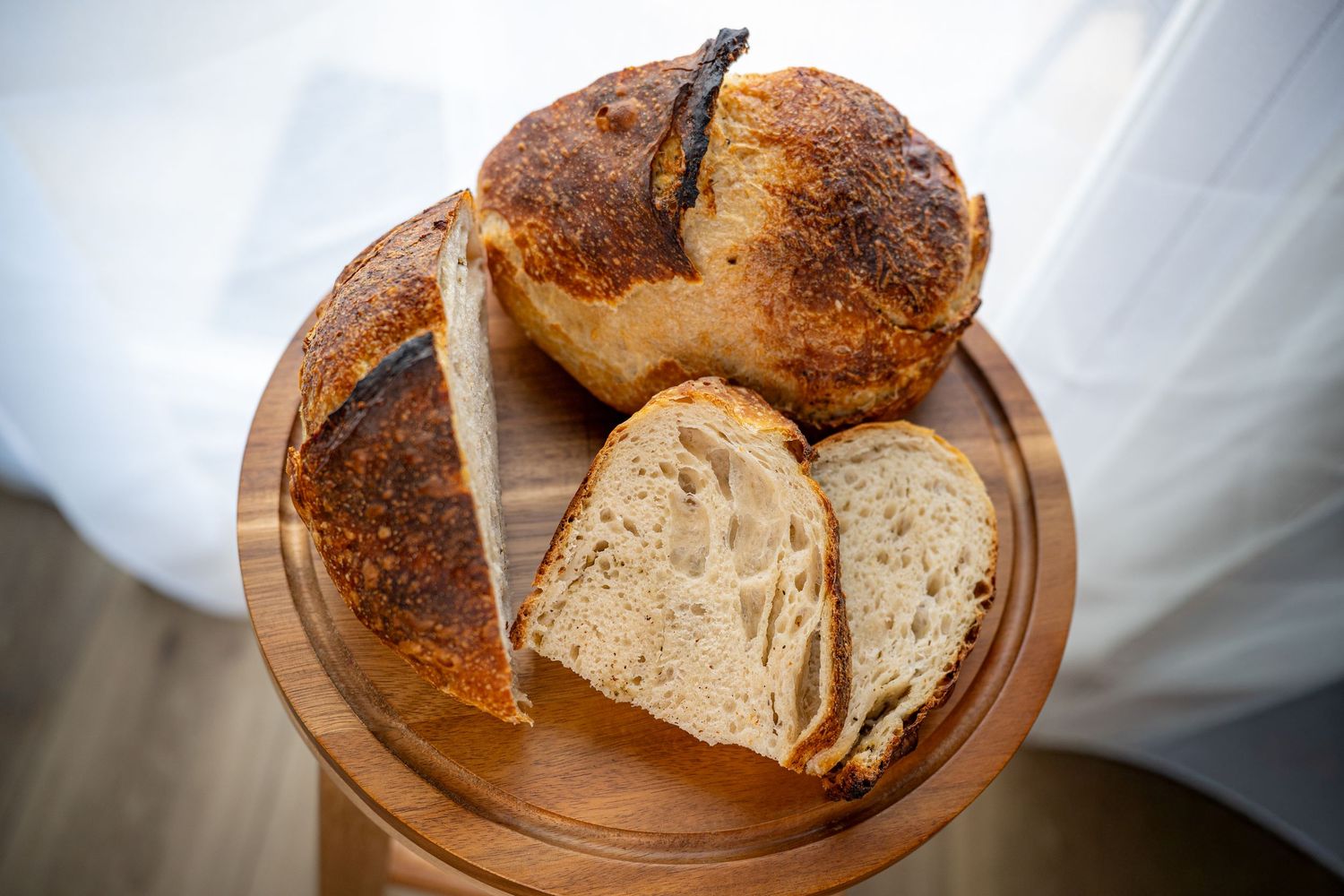 Sliced rustic sourdough bread arranged on a wooden cutting board against a white background.