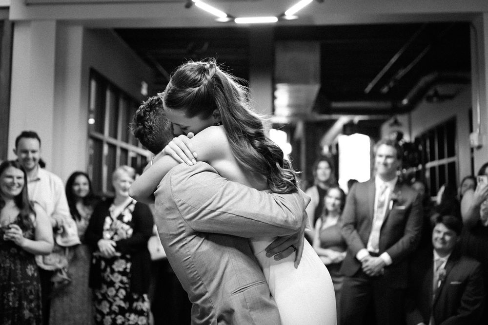 A couple shares an intimate dance moment at their wedding reception while guests look on with joy.