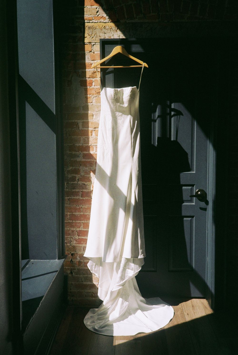 A series of white curtains billowing in sunlight against exposed brick walls creating dramatic shadows and contrast.
