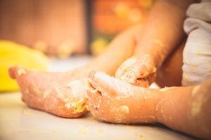 Close-up of a baby's feet and hands covered in smashed birthday cake during a first birthday cake smash.