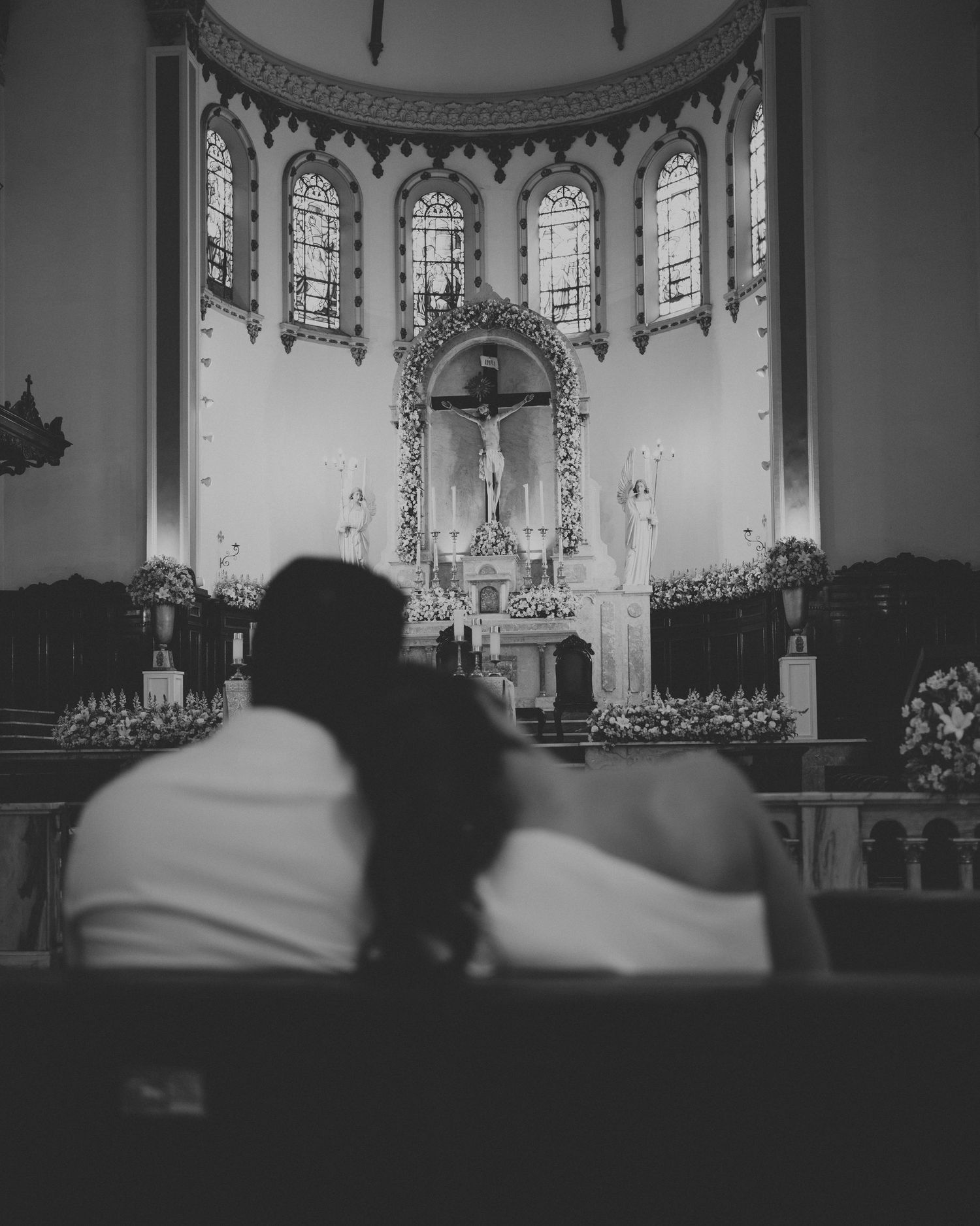 Fotografia de casamento em igreja com noivos em silhueta diante de altar imponente e vitrais clássicos transmitindo um momento de paz