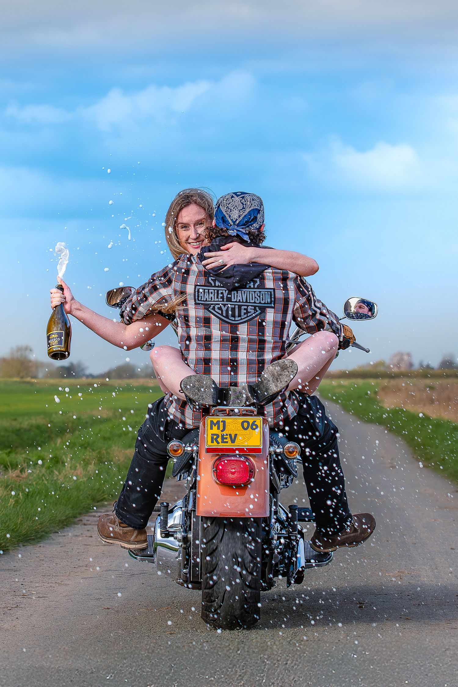 A sequence of four photos showing a motorcycle rider popping open a champagne bottle while sitting on a parked bike.