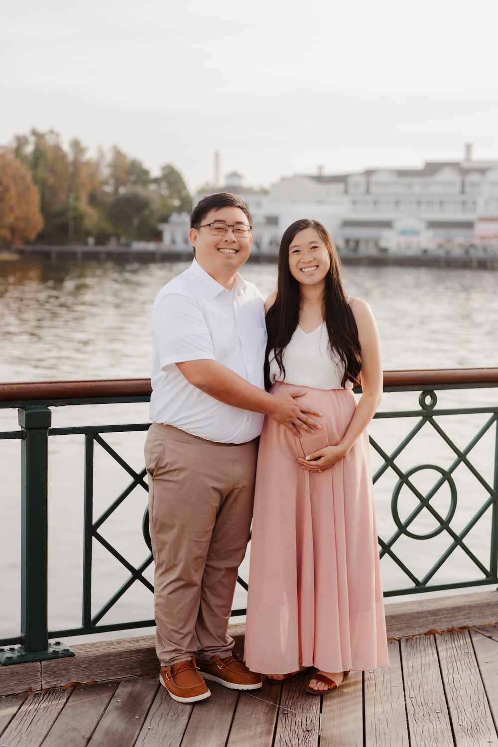 A couple shares a romantic moment on a waterfront boardwalk during an engagement photoshoot.