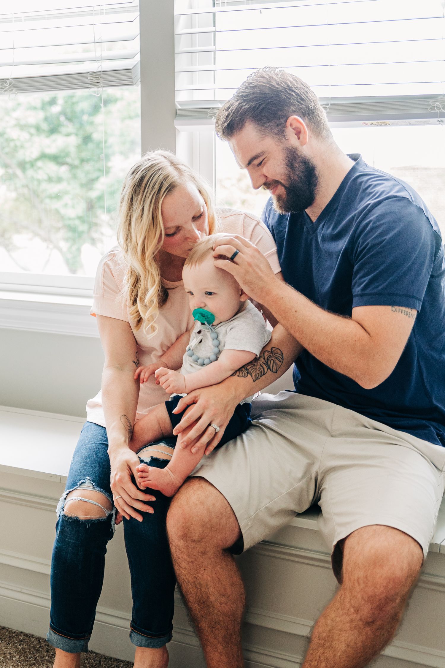 A tender family moment captured in a series of photos showing parents bonding with their newborn baby near a window.