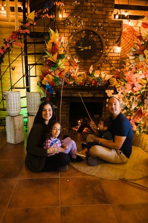 A series of playful poses captured on the floor against a brick wall with autumn decorations and twinkling lights.