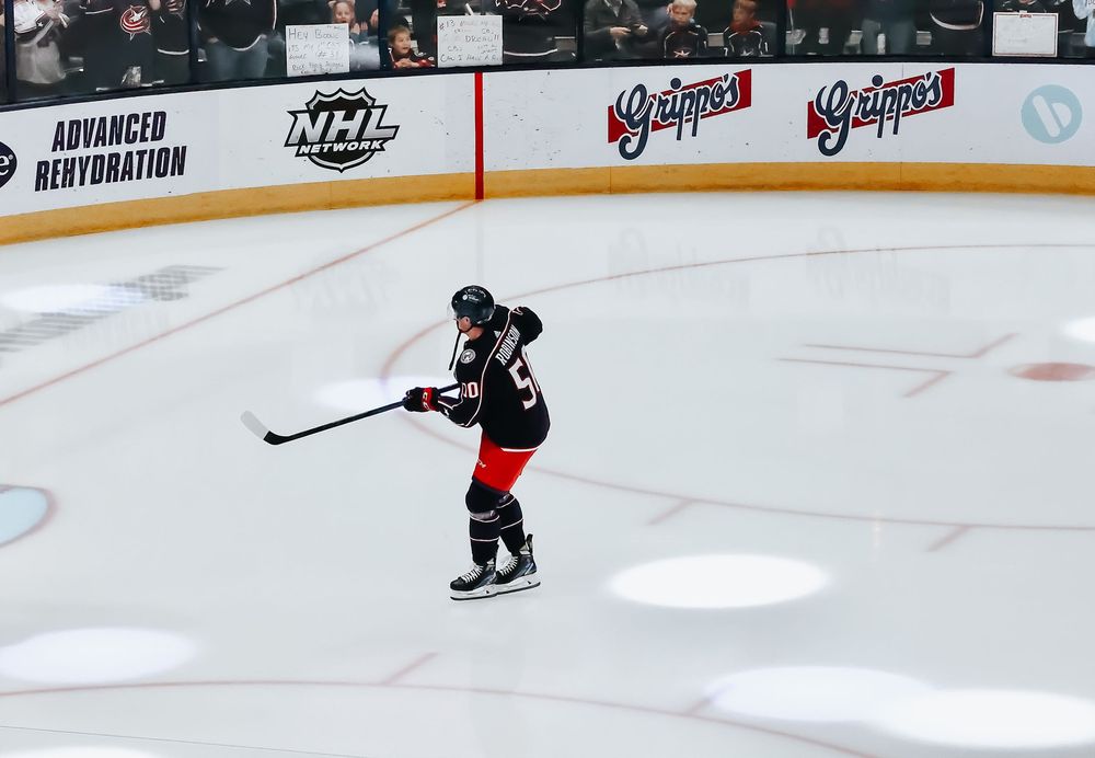 A hockey player in a black jersey takes a shot on the ice during an NHL game.