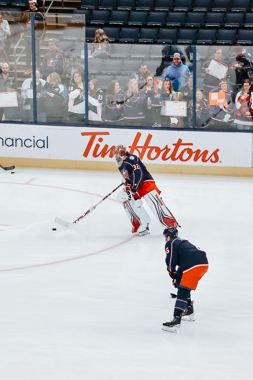 Hockey players on ice rink with Tim Hortons advertising boards visible in background during game action.