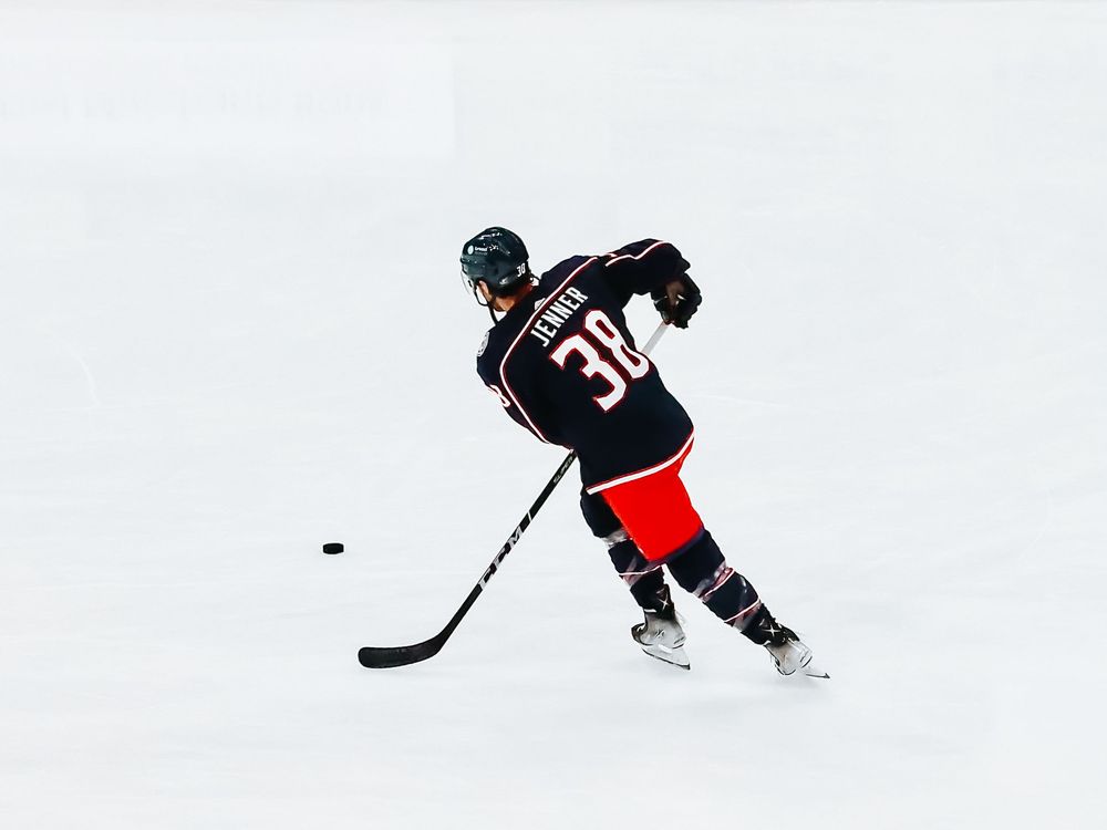 Ice hockey player in black jersey number 30 skates on rink during game action.