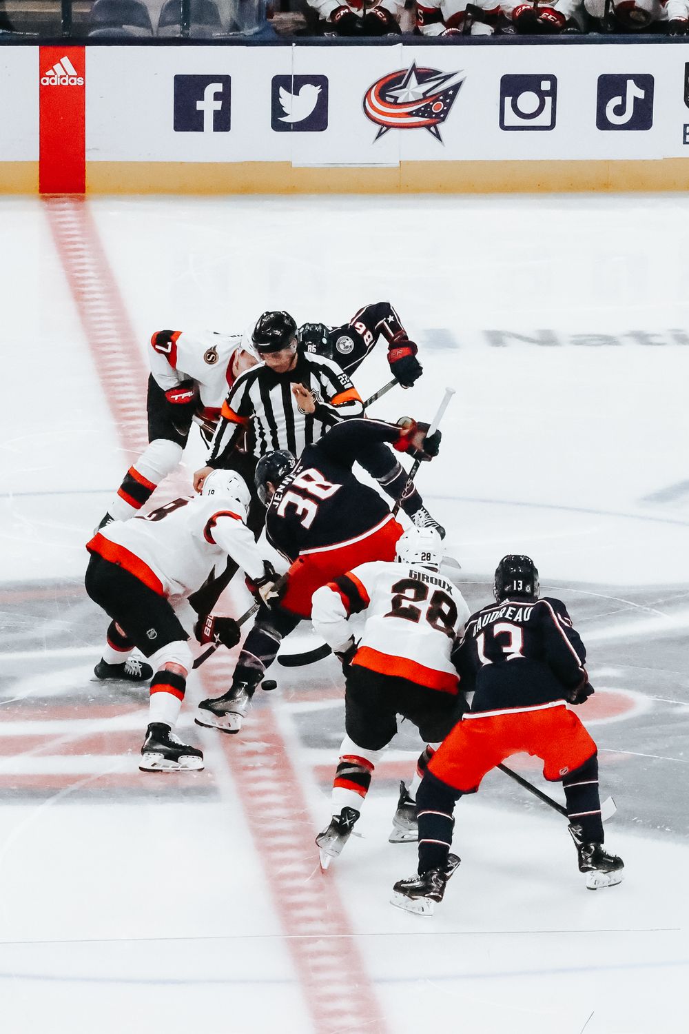 NHL hockey players from opposing teams battle for the puck during an intense game on the ice.