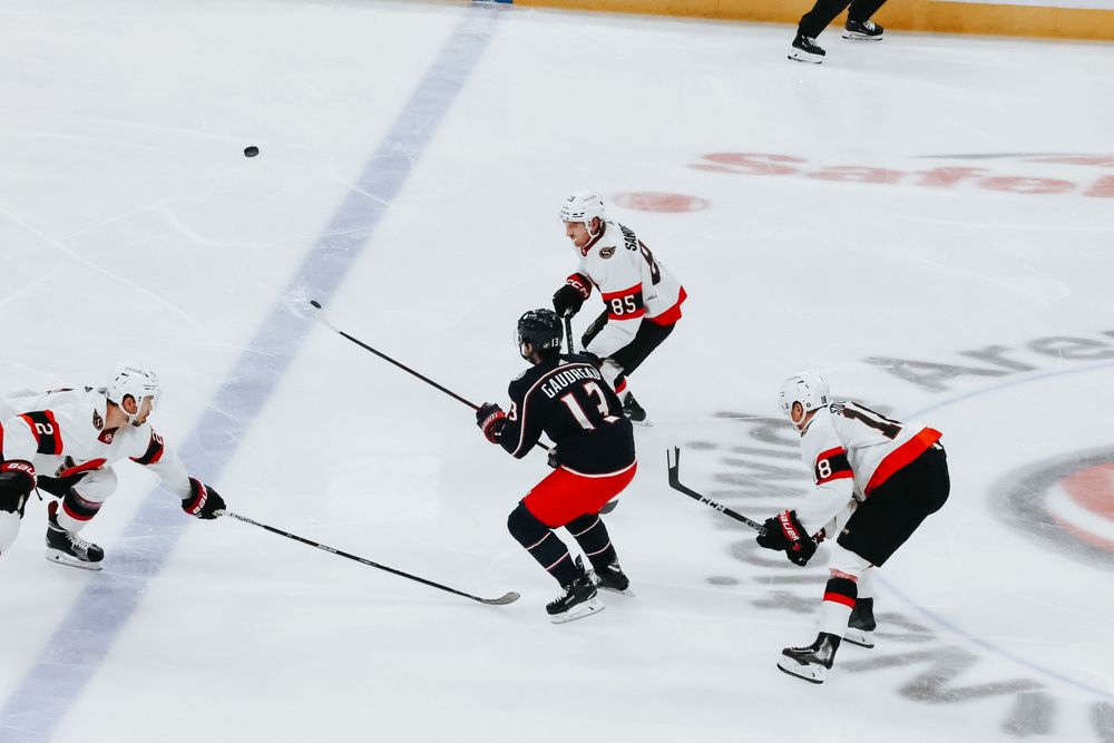 Ice hockey players in black and white jerseys battle for the puck during an intense game.