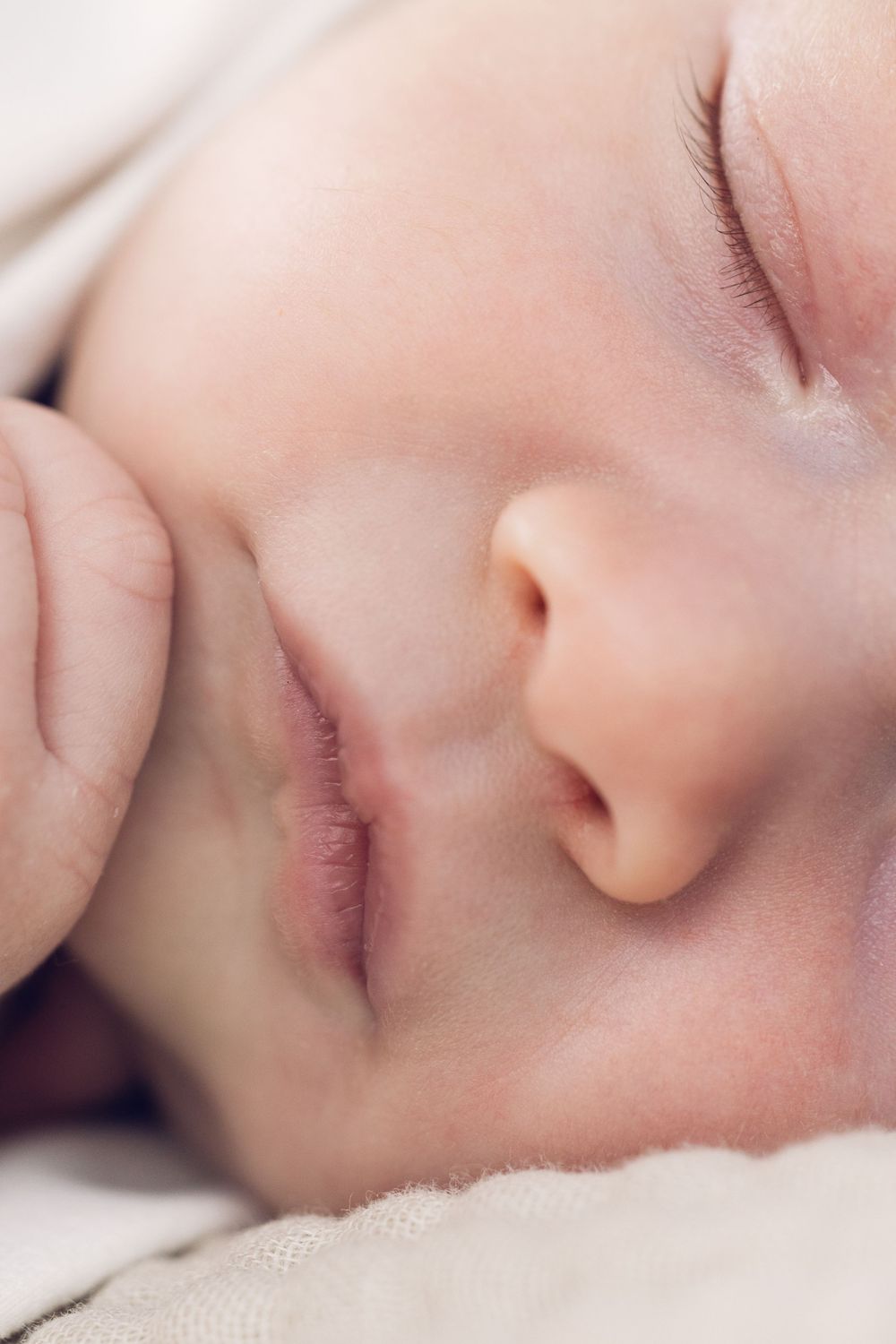 Extreme close-up of a sleeping newborn baby's face showing tiny lips and nose.