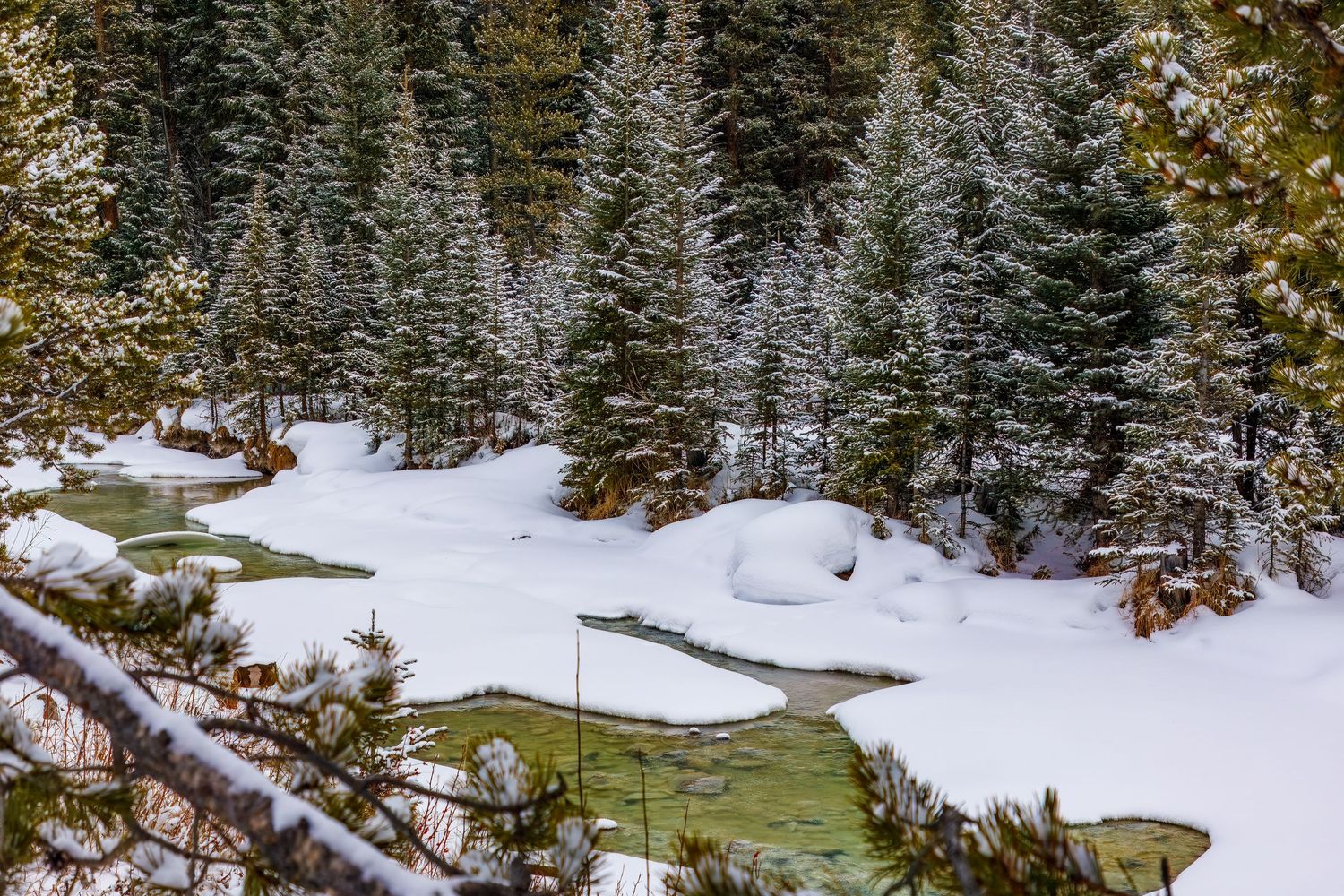 Long exposure winter river landscape photography showing winding river thru snowy mountain forests, calming nature wall art.