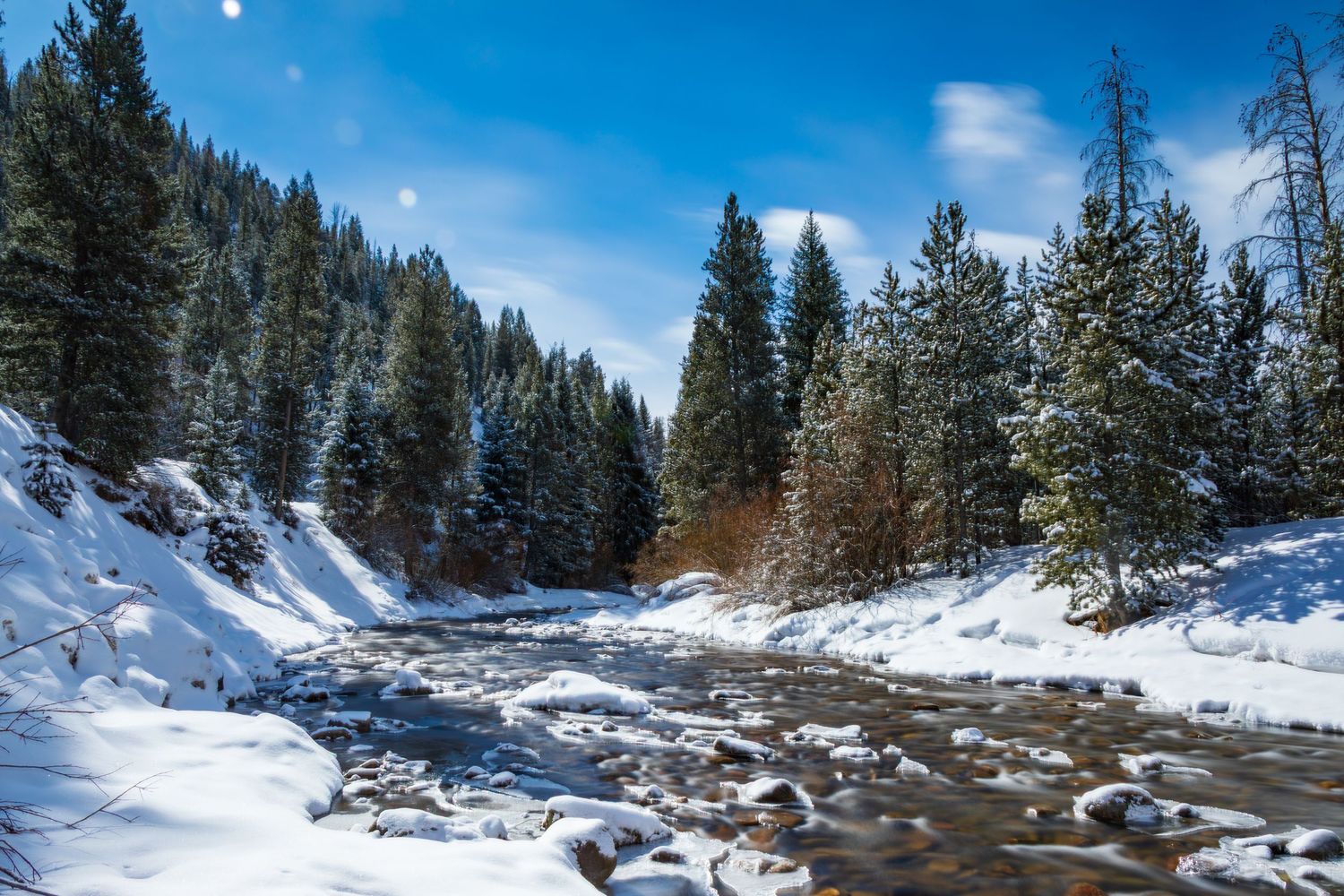 Long exposure winter river landscape photography showing winding river thru snowy mountain forests, calming nature wall art.
