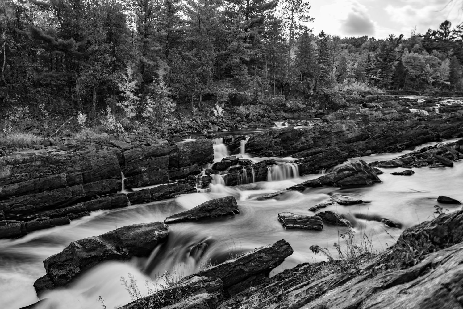 Long exposure black and white fall waterfall landscape photography showing cascading water over rocks in forests, calming nature wall art.