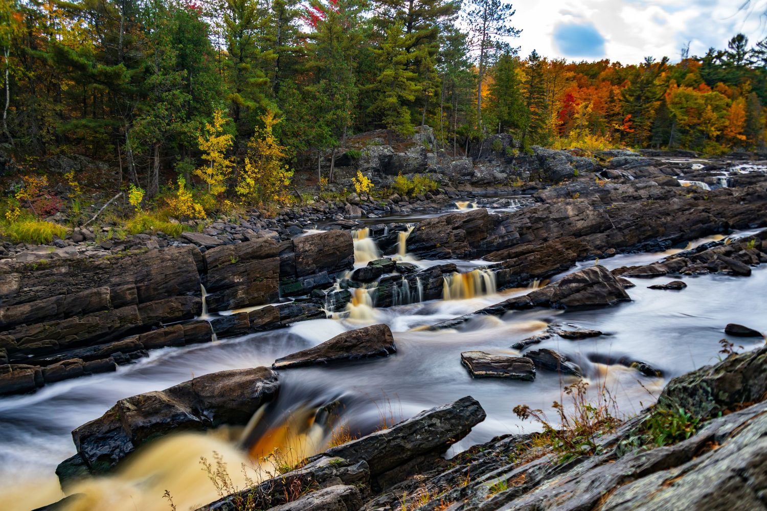 Long exposure fall waterfall landscape photography showing cascading water over mossy rocks in forests of Jay Cook, calming nature wall art.