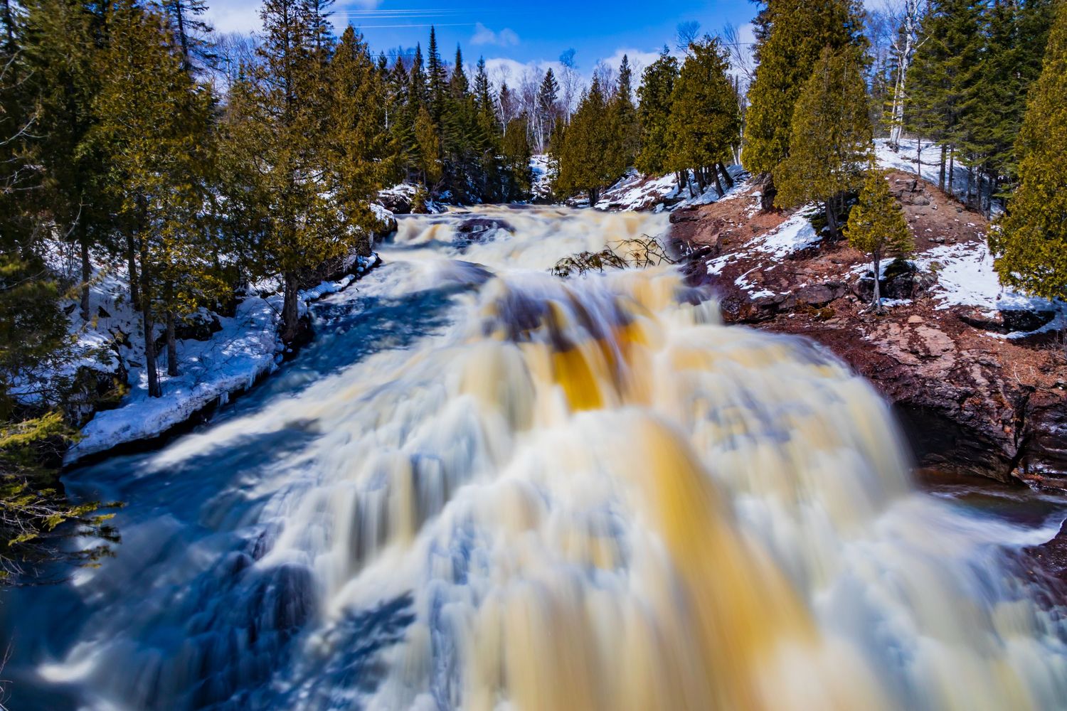 Long exposure waterfall landscape photography showing cascading water over mossy rocks in forests of Northern MN, calming nature wall art.
