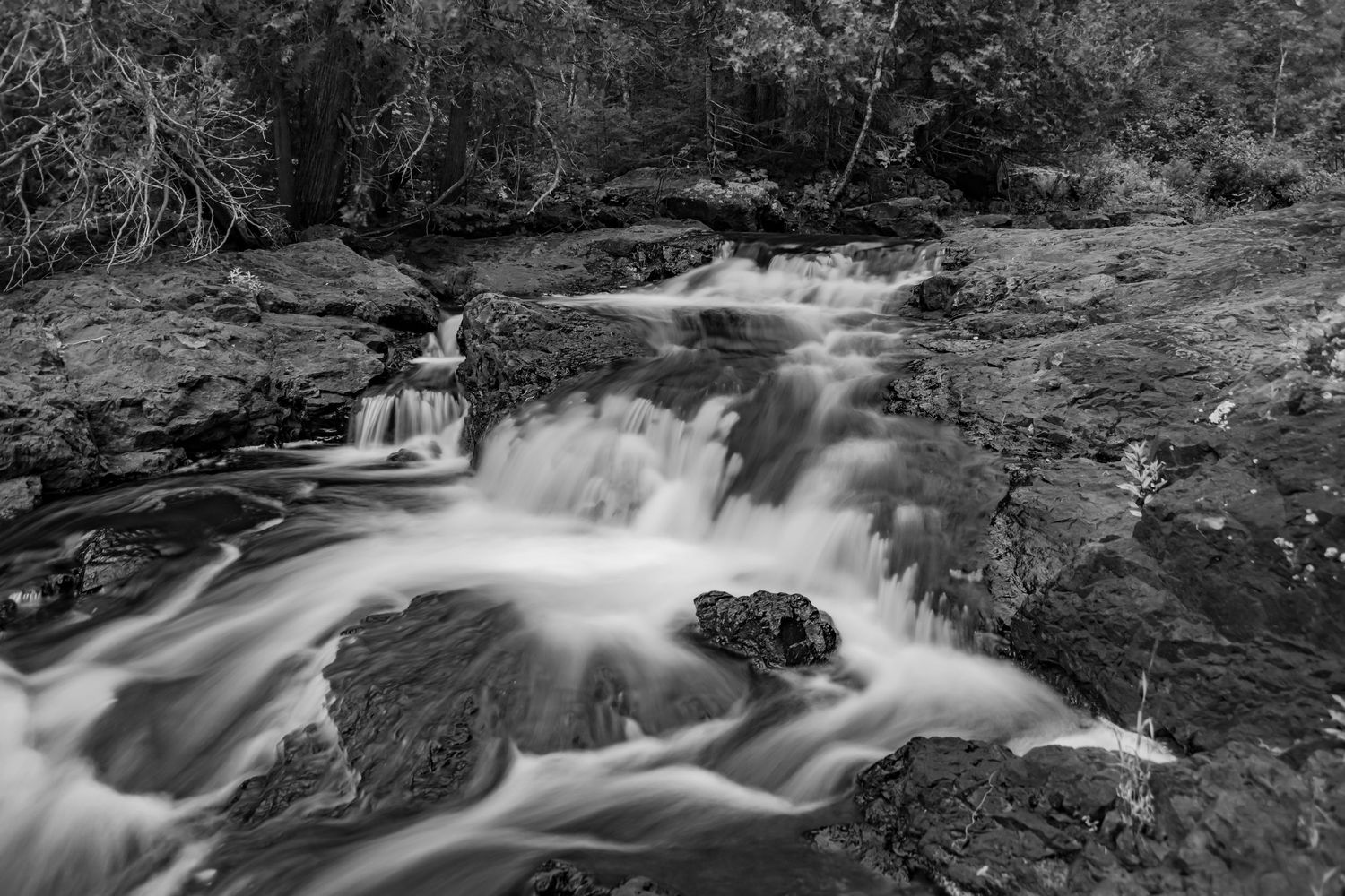 Long exposure waterfall landscape photography showing cascading water over mossy rocks in forests of Northern MN, calming nature wall art.