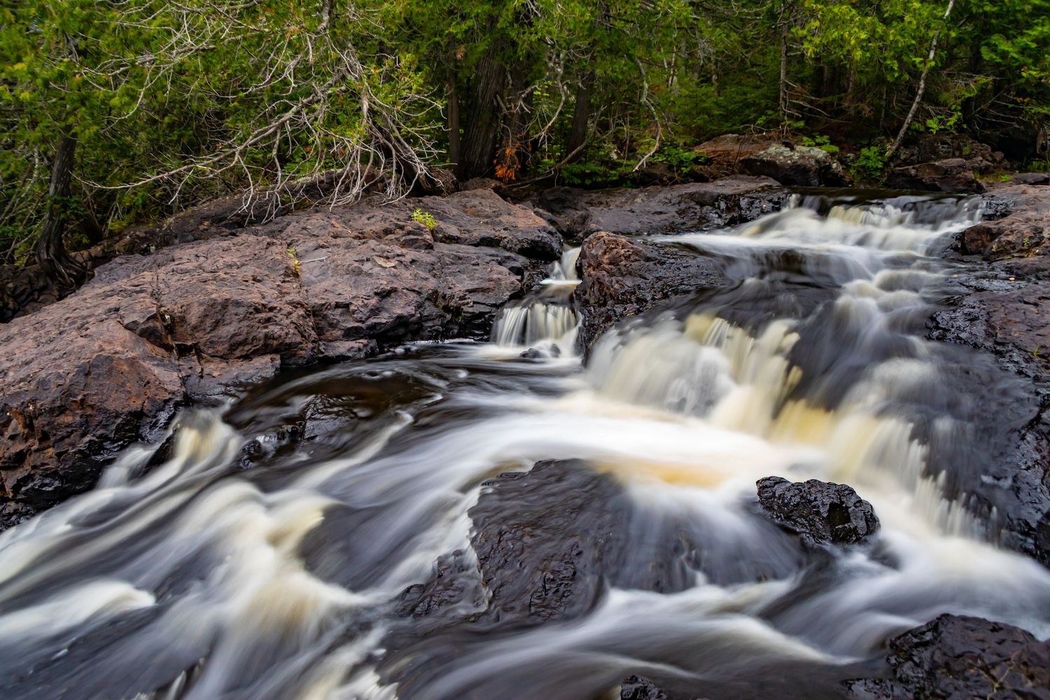Long exposure waterfall landscape photography showing cascading water over mossy rocks in forests of Northern MN, calming nature wall art.