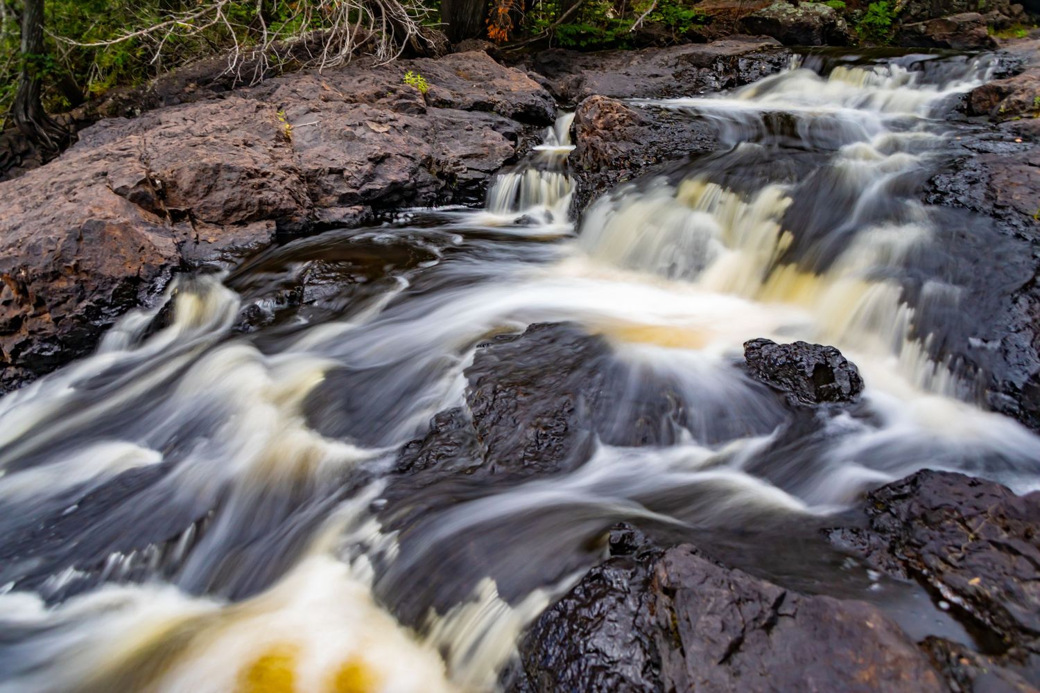 Long exposure waterfall landscape photography showing cascading water over mossy rocks in forests of Northern MN, calming nature wall art.