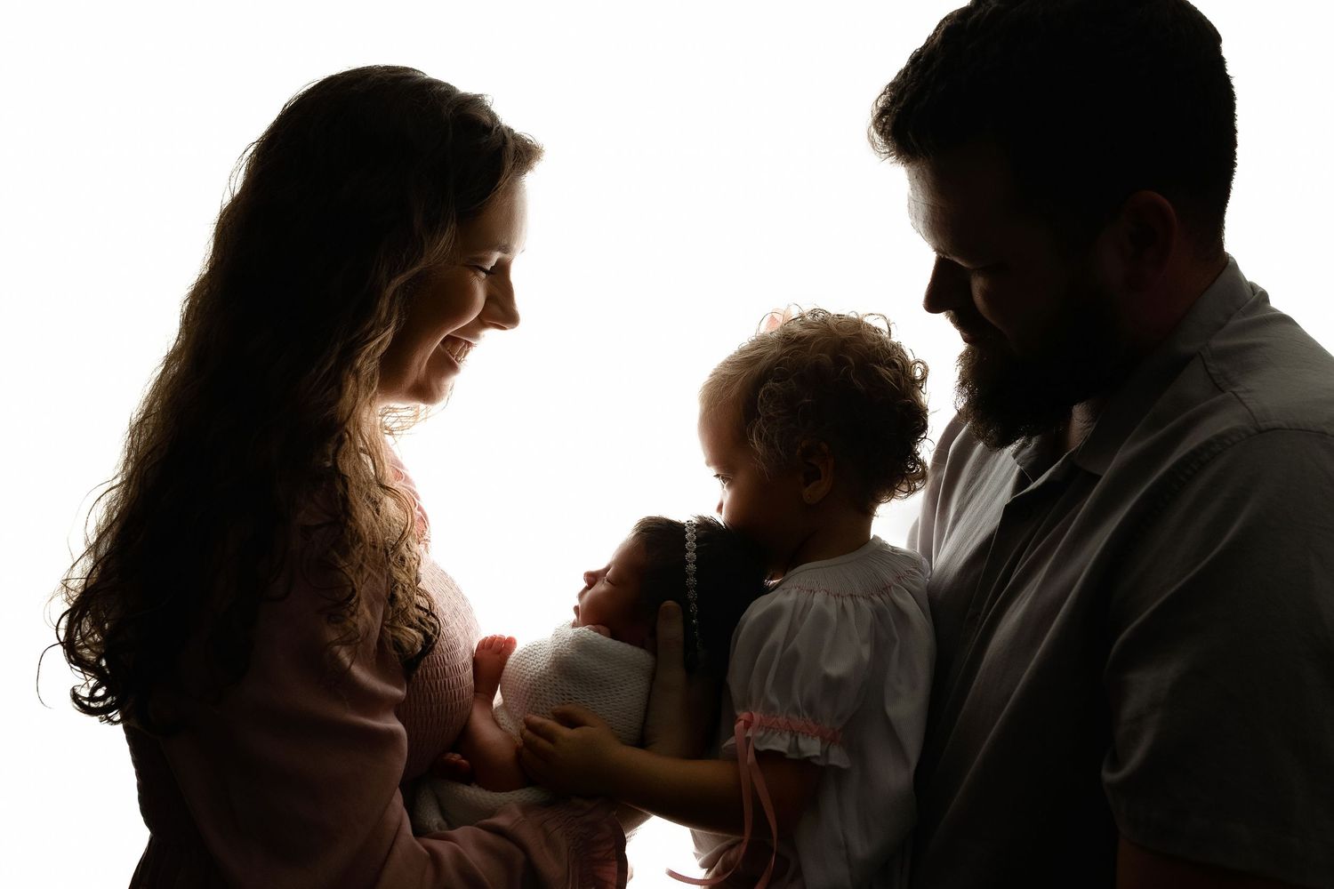 Family is backlit and big sister kissing baby. Greenville, SC newborn photographer, Easley, SC newborn photographer, Upstate, SC newborn pho