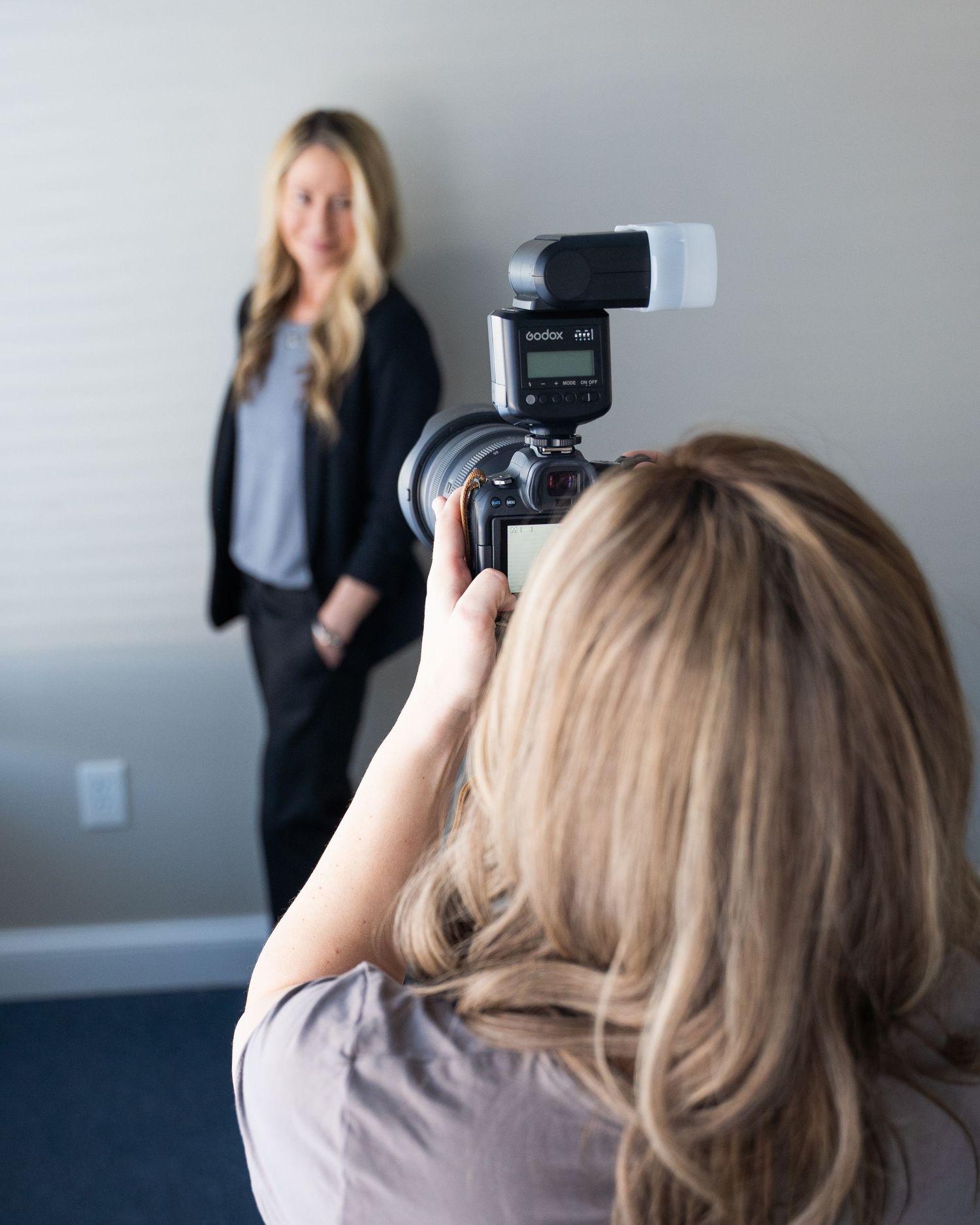 Behind the scenes view of a photo shoot in progress showing camera equipment and lighting setup in a bright studio.