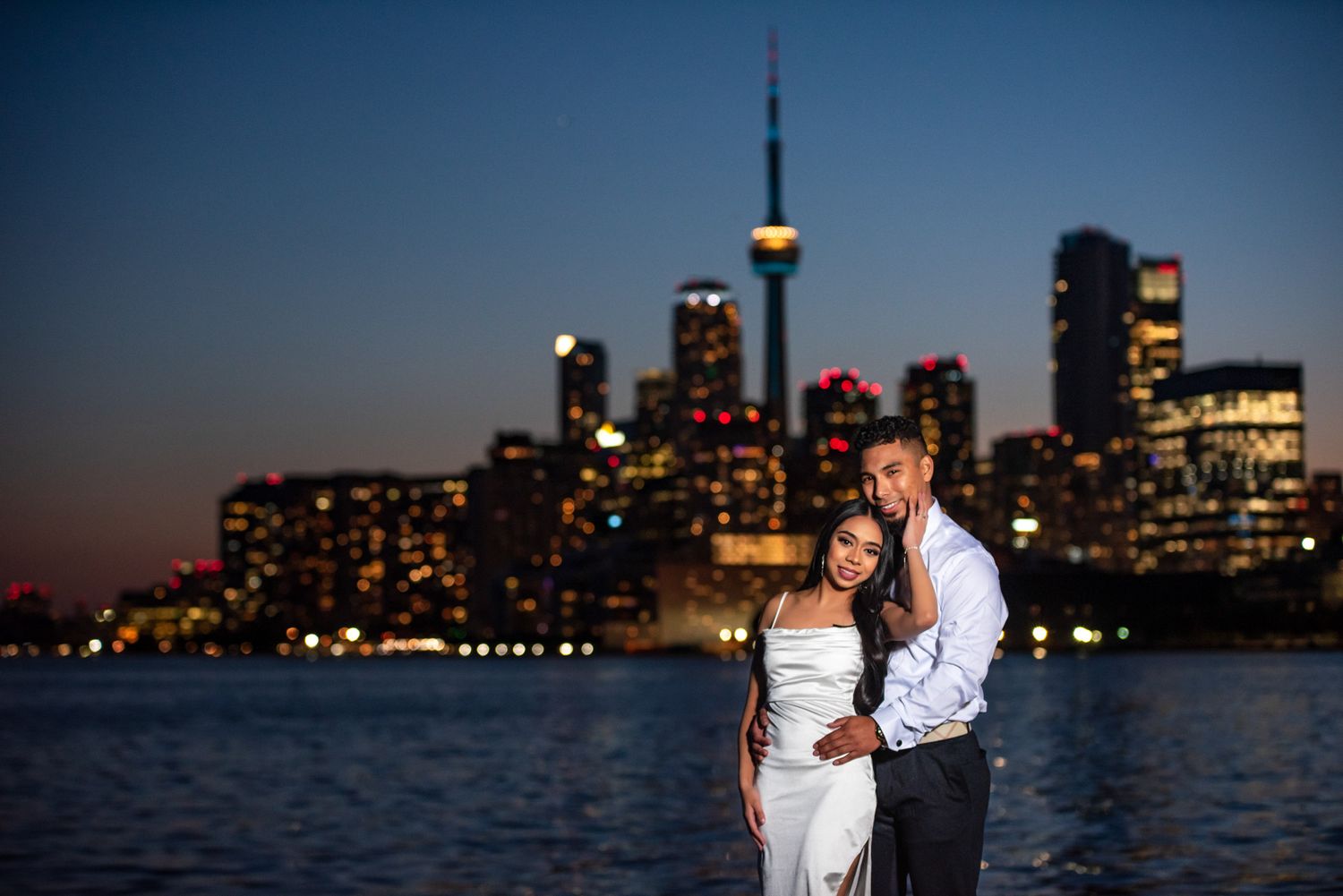 Couple embracing at sunset with the Toronto skyline and CN Tower in the background. Romantic engagement photography in Toronto.
