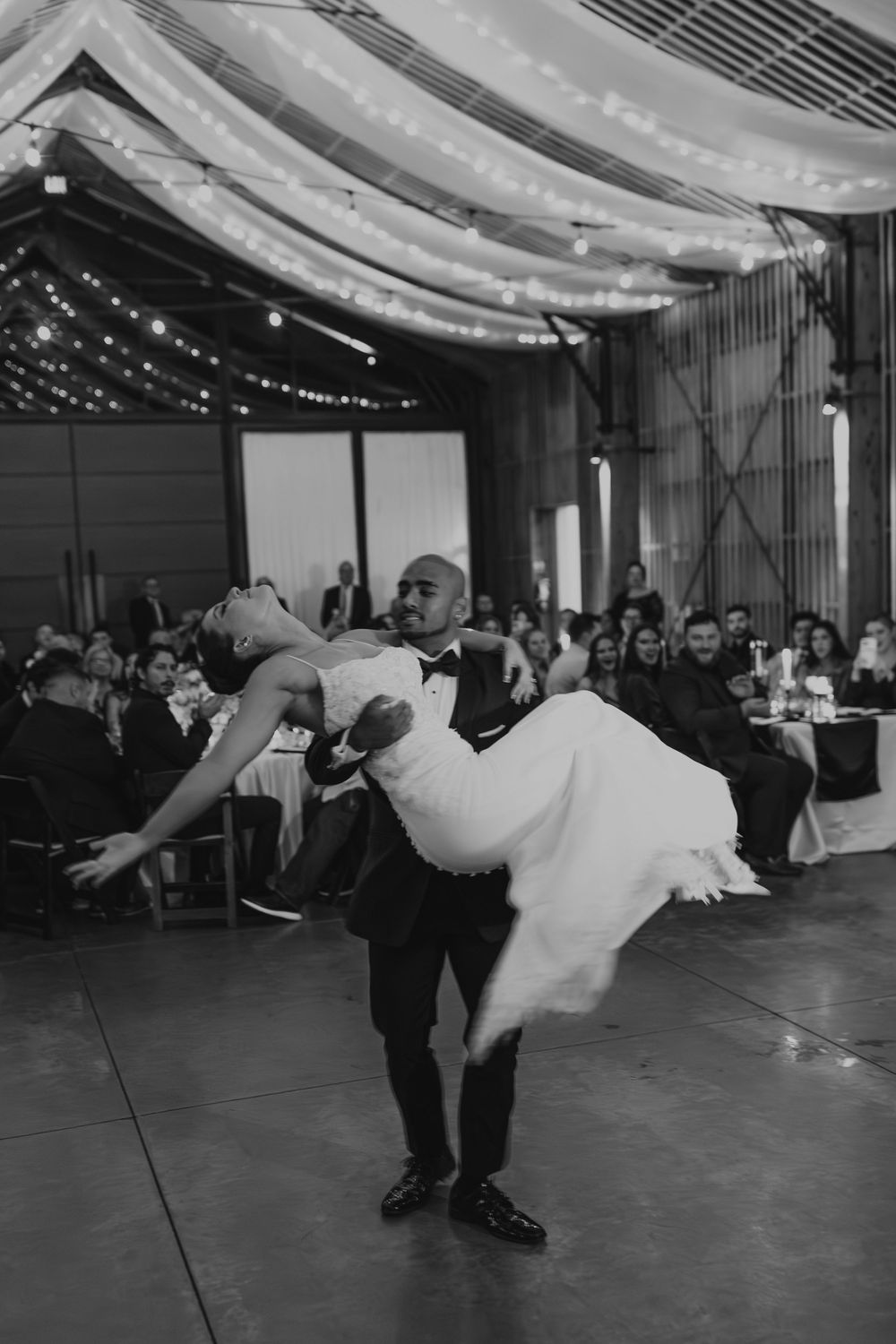 A dramatic wedding dance dip sequence showing a couple performing on the dance floor under draped lighting at a reception.