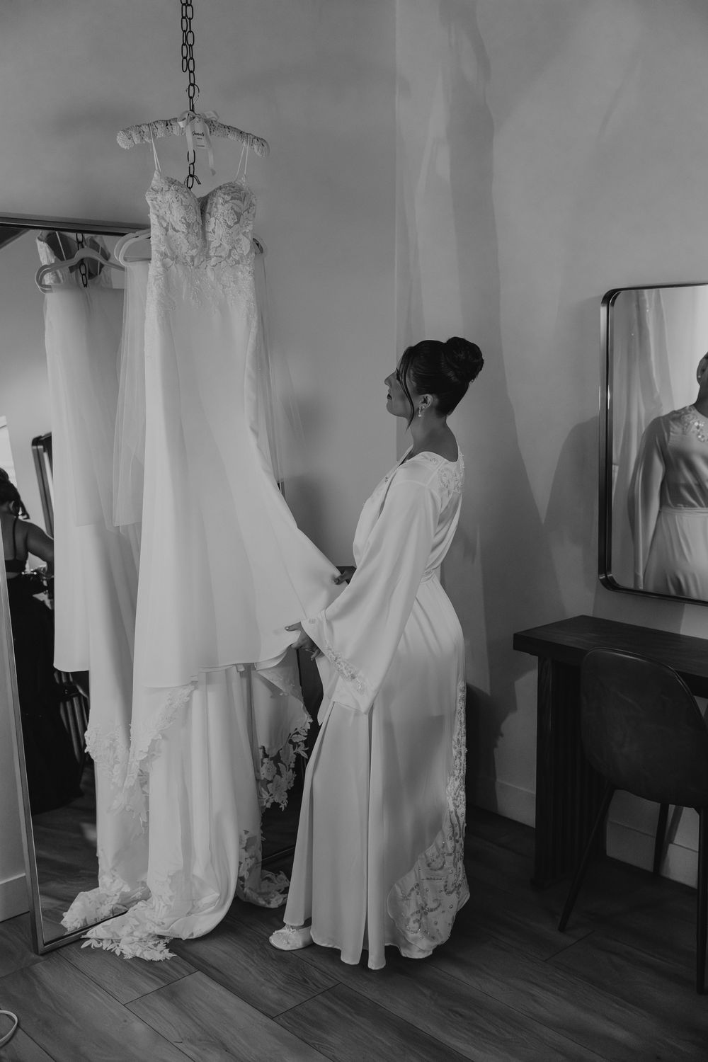 A series of black and white photographs showing a wedding dress being fitted and adjusted in a dressing room.
