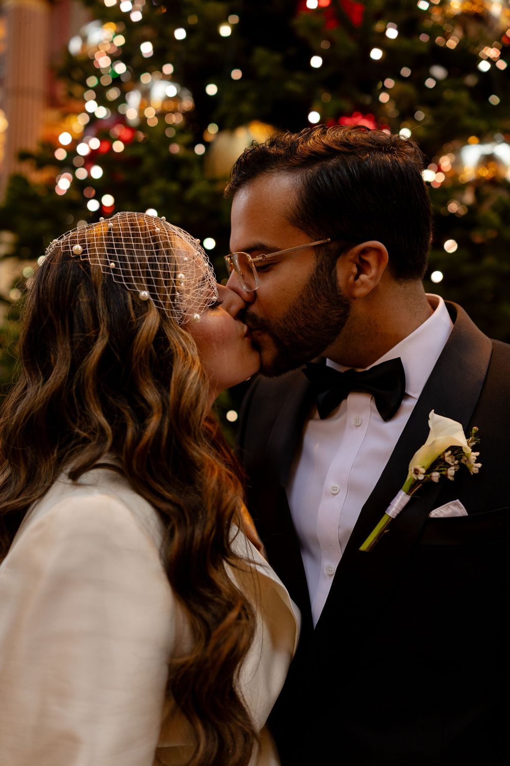 Romantic wedding moment with bokeh lights and Christmas decorations in the background.