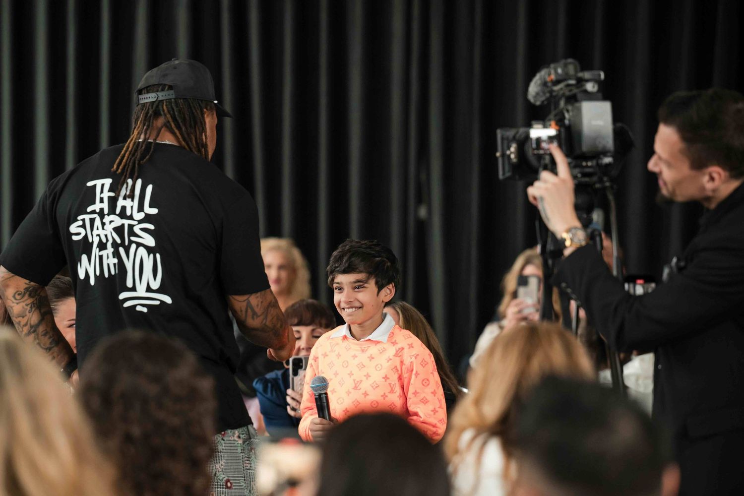 Chicago videographer Nate Templeton recording a candid moment at a conference with a speaker talking to a young smiling attendee.