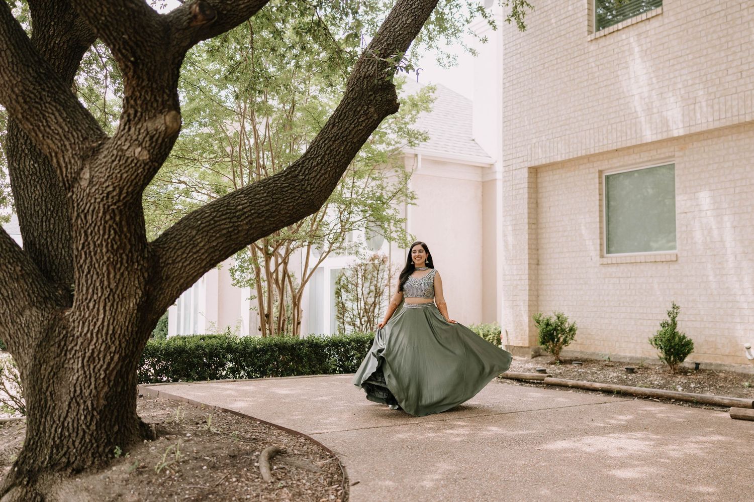 A bride in red surrounded by bridesmaids wearing neutral tones on a manicured lawn.
