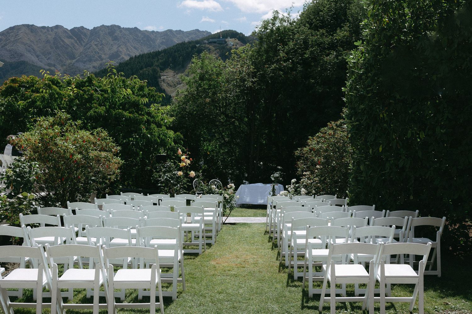 White chairs arranged in rows for an outdoor intimate Queenstown wedding ceremony with mountains  in the background.
