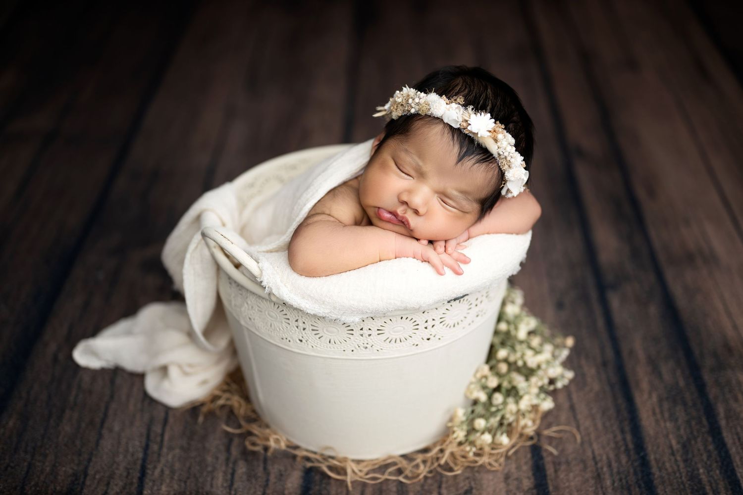 A series of newborn photography portraits showing a sleeping baby in white bowls with soft lighting and floral accents.