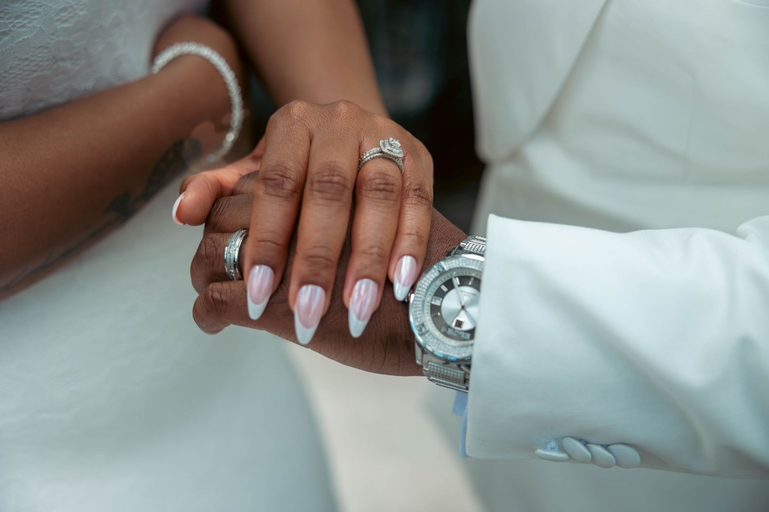 Close-up of a bride and grooms hands showing wedding rings and manicured nails.