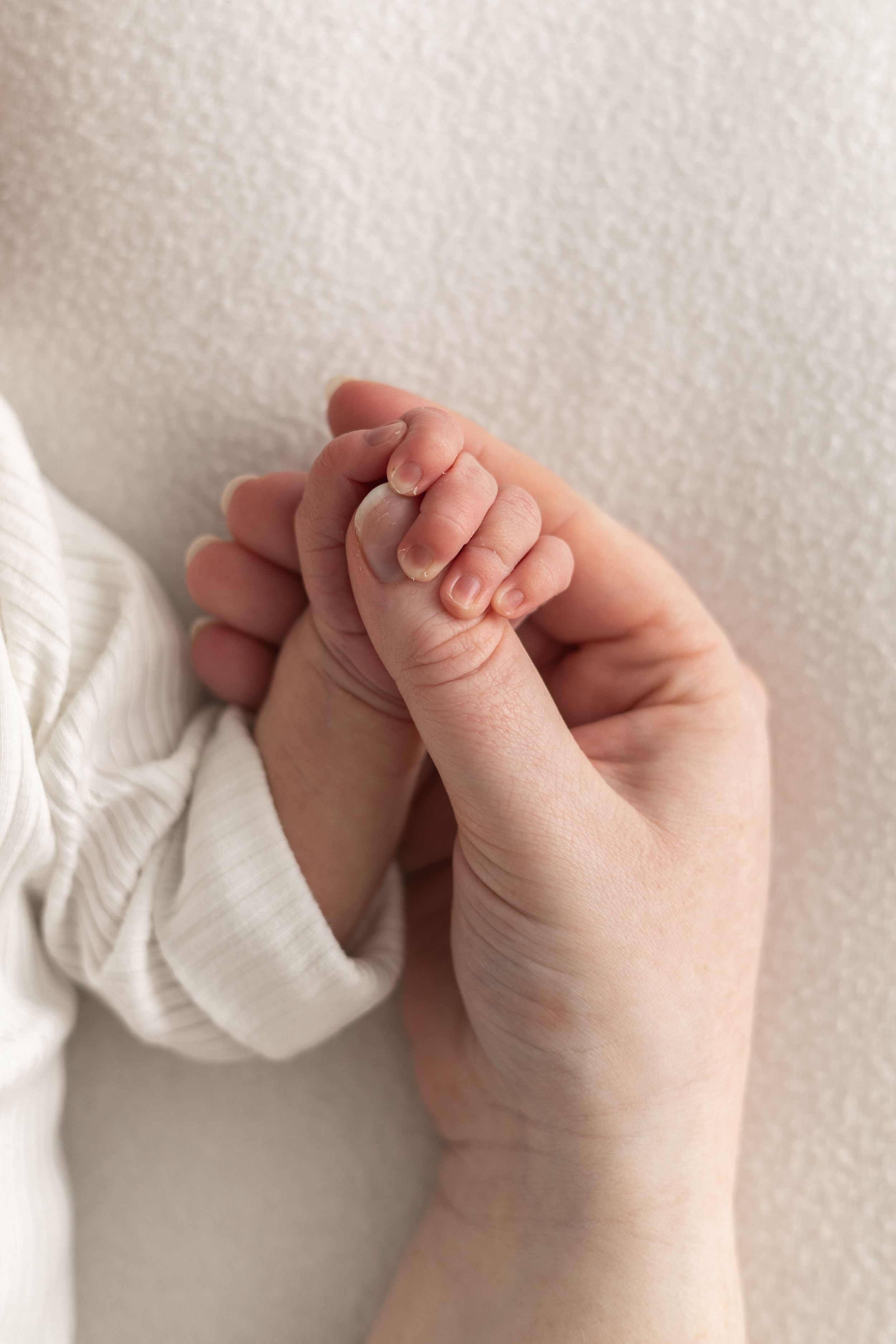 A newborn baby grasping mums finger, relaxed newborn photoshoot Nottingham